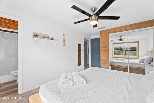 bedroom with ceiling fan, wood-type flooring, ensuite bathroom, and a closet