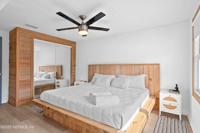 bedroom with ceiling fan, a closet, and light hardwood / wood-style flooring