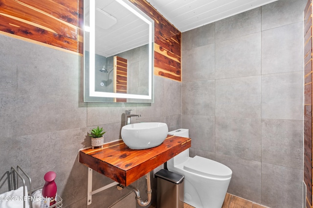 bathroom featuring toilet, sink, and tile walls