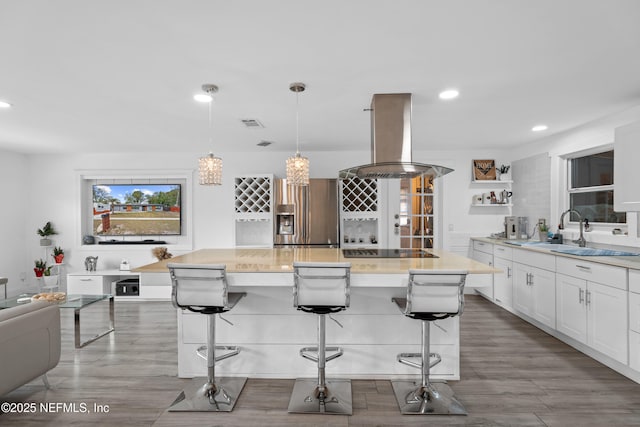 kitchen with hanging light fixtures, island range hood, a breakfast bar area, and white cabinets