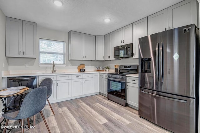 kitchen featuring appliances with stainless steel finishes, light hardwood / wood-style floors, and sink