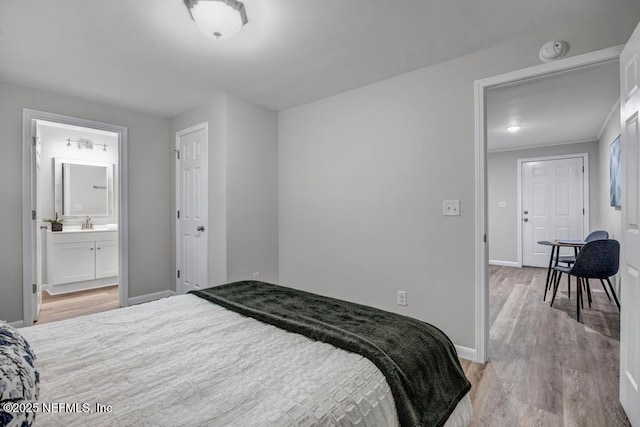 bedroom with connected bathroom, sink, and light wood-type flooring