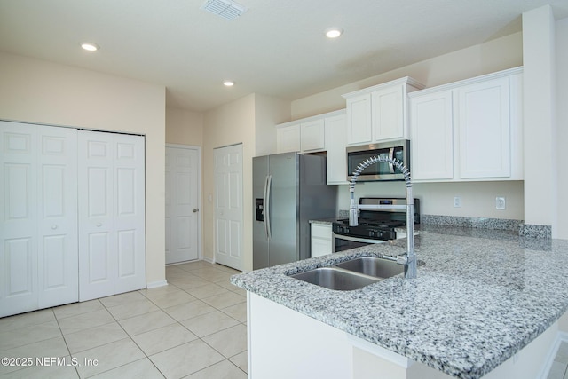 kitchen featuring light tile patterned flooring, stainless steel appliances, kitchen peninsula, and white cabinets