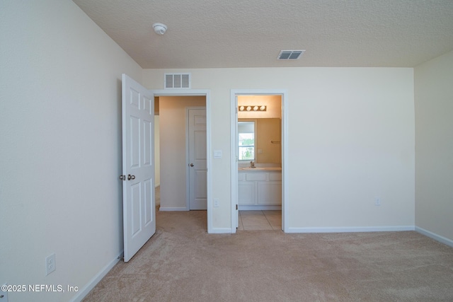 unfurnished bedroom with sink, light colored carpet, and a textured ceiling