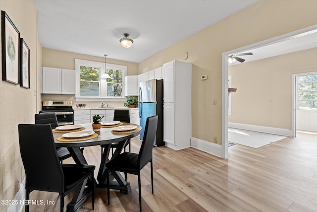 dining room with a ceiling fan, baseboards, and light wood finished floors