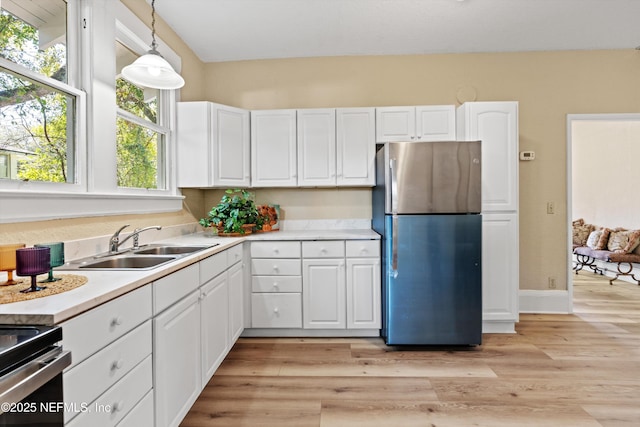 kitchen featuring stainless steel appliances, hanging light fixtures, light countertops, and white cabinetry