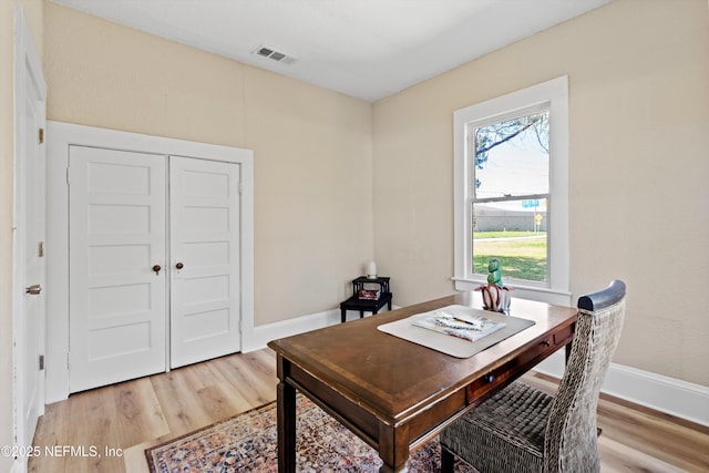 office area with light wood-style flooring, visible vents, and baseboards