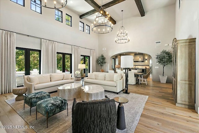 living room with beam ceiling, light wood-type flooring, and a notable chandelier