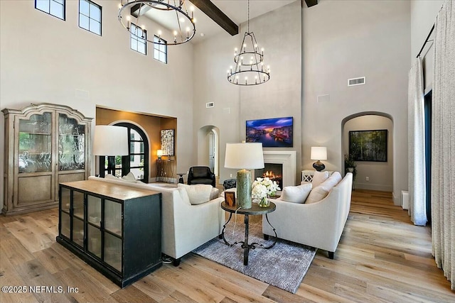 living room featuring beamed ceiling, a chandelier, and light hardwood / wood-style floors