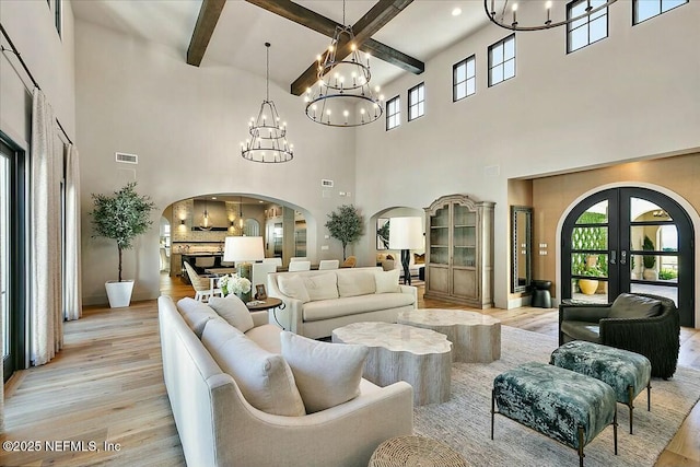 interior space featuring french doors, beamed ceiling, an inviting chandelier, and light hardwood / wood-style floors