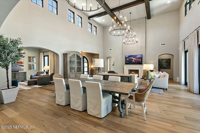 dining space featuring beam ceiling, a notable chandelier, and light hardwood / wood-style floors