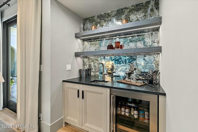 bar with wine cooler, sink, white cabinetry, and light wood-type flooring