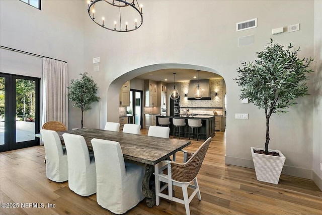 dining space with french doors, an inviting chandelier, and light hardwood / wood-style flooring