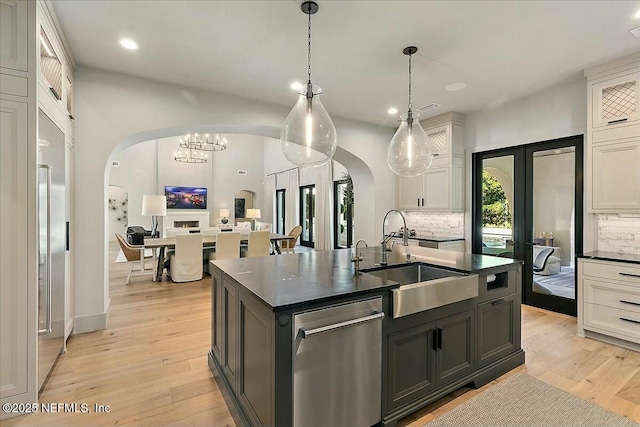 kitchen with white cabinetry, sink, pendant lighting, and a kitchen island with sink