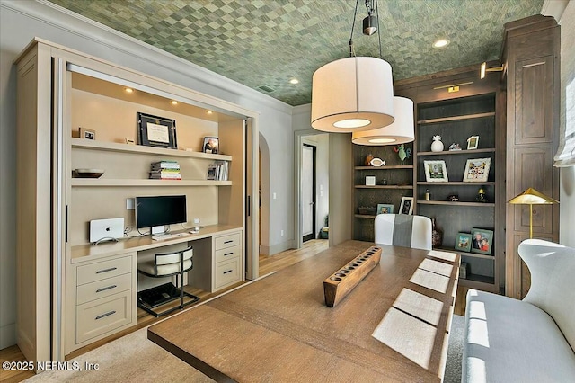 home office with built in desk, brick ceiling, crown molding, light wood-type flooring, and built in shelves