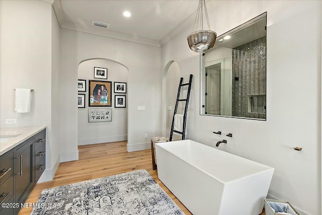 bathroom featuring ornamental molding, vanity, independent shower and bath, and wood-type flooring