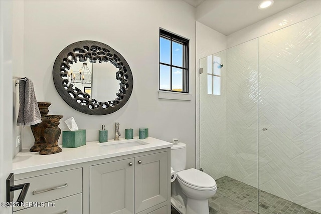 bathroom with vanity, toilet, and tiled shower