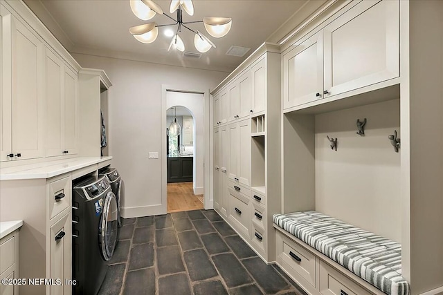 washroom with an inviting chandelier, cabinets, and washing machine and clothes dryer