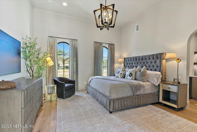 bedroom featuring an inviting chandelier, crown molding, and light hardwood / wood-style floors