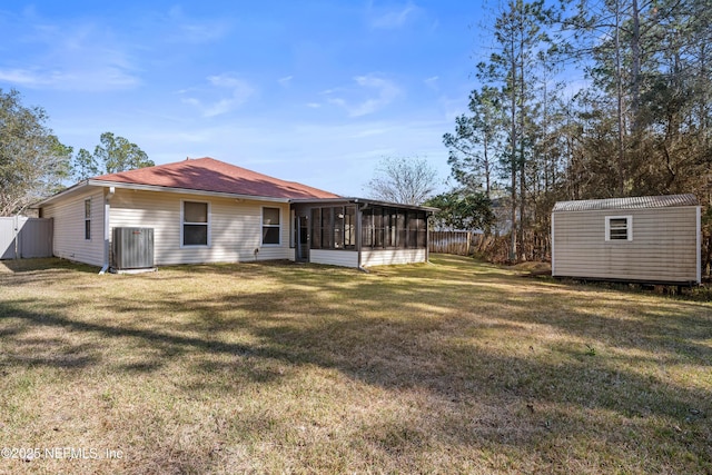 rear view of property with cooling unit, a yard, a sunroom, and a storage unit