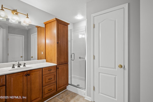 bathroom with tile patterned flooring, vanity, a shower with shower door, and a textured ceiling