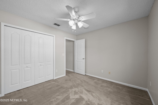 unfurnished bedroom featuring ceiling fan, light carpet, a closet, and a textured ceiling