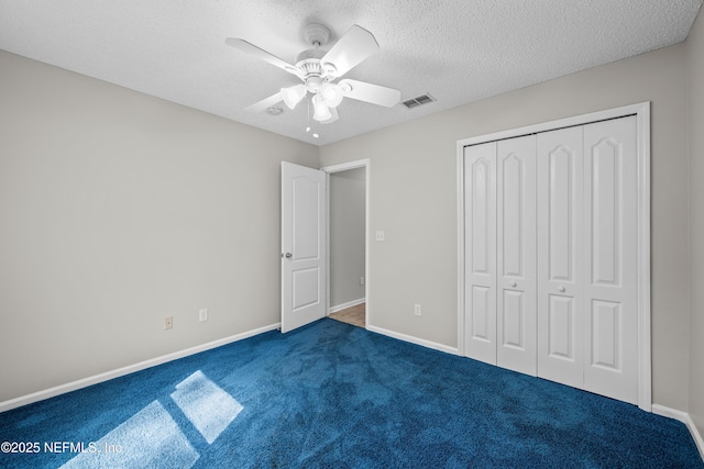 unfurnished bedroom with dark carpet, ceiling fan, a closet, and a textured ceiling