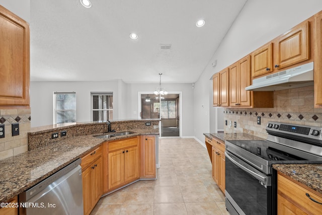 kitchen with sink, hanging light fixtures, light tile patterned floors, appliances with stainless steel finishes, and dark stone counters