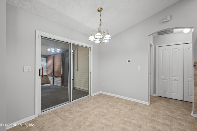 tiled spare room with an inviting chandelier and a textured ceiling