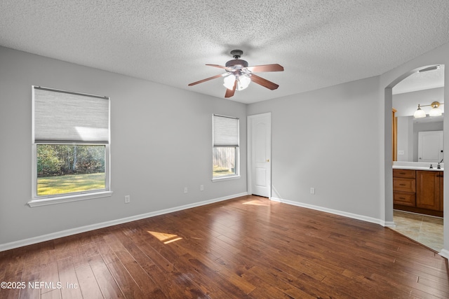 unfurnished room featuring a textured ceiling, dark hardwood / wood-style floors, and a healthy amount of sunlight