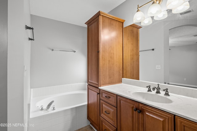 bathroom with vanity, tiled bath, and a textured ceiling