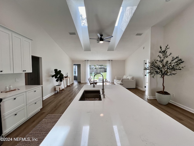 kitchen with white cabinetry, dark hardwood / wood-style flooring, a skylight, and sink