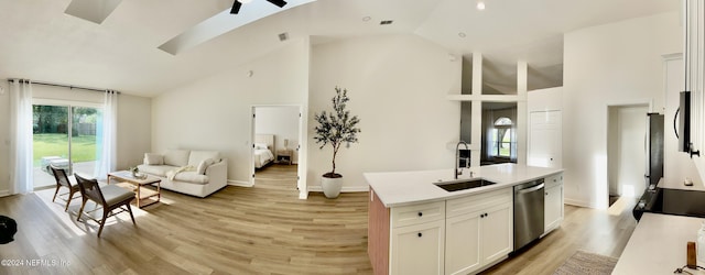 kitchen with sink, appliances with stainless steel finishes, a kitchen island with sink, white cabinetry, and light hardwood / wood-style floors