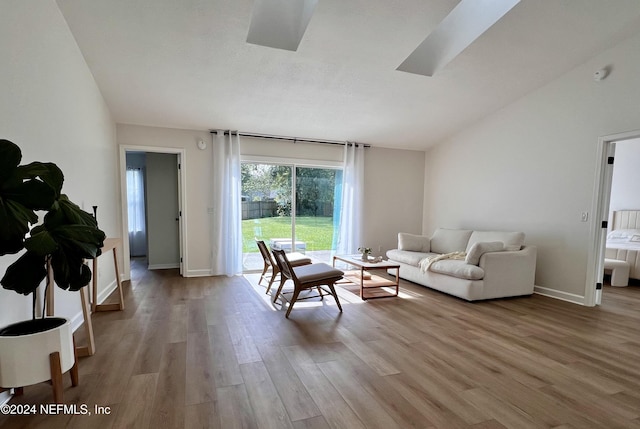 living room with vaulted ceiling with skylight and light wood-type flooring