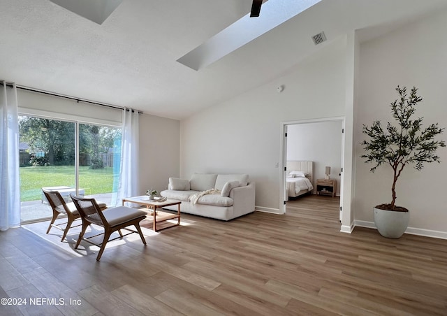 living room featuring hardwood / wood-style flooring, high vaulted ceiling, and a textured ceiling