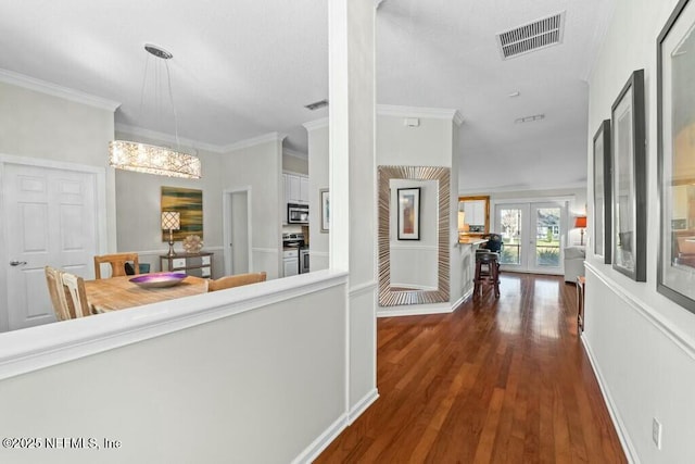 corridor featuring dark wood-type flooring, french doors, visible vents, and crown molding