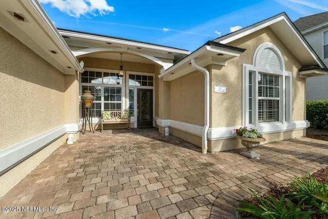 view of exterior entry with a patio area and stucco siding