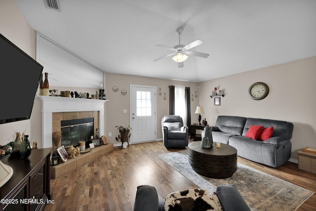 living room with a tiled fireplace, hardwood / wood-style floors, and ceiling fan