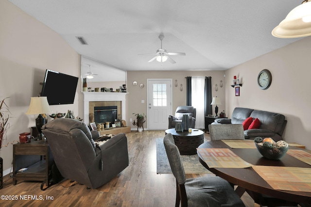 living room with dark wood-type flooring, ceiling fan, lofted ceiling, and a fireplace