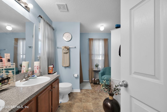 bathroom featuring vanity, a textured ceiling, and toilet