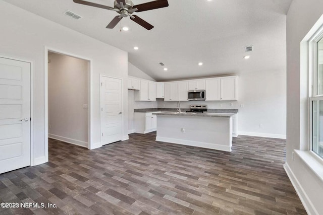 kitchen with an island with sink, lofted ceiling, white cabinetry, stainless steel appliances, and dark wood-type flooring