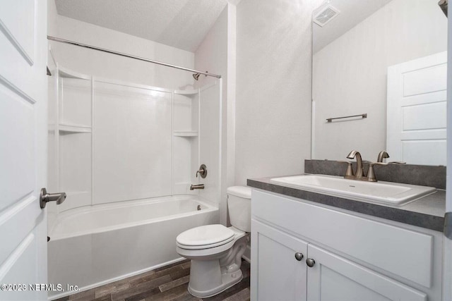 full bathroom with wood-type flooring, vanity,  shower combination, toilet, and a textured ceiling