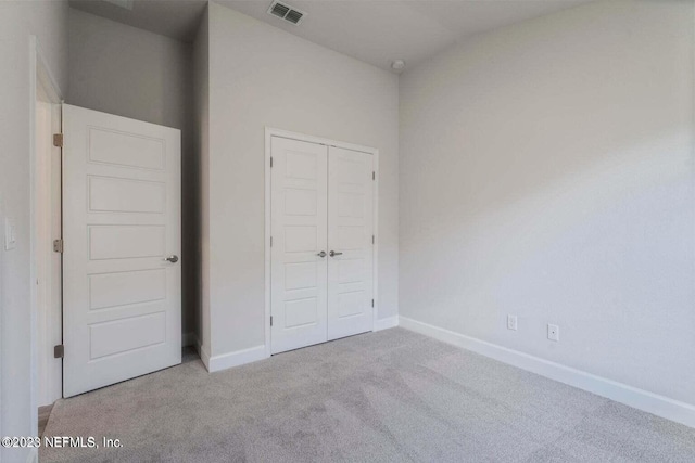 unfurnished bedroom with light carpet and a closet