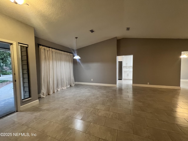 unfurnished room featuring lofted ceiling and a textured ceiling