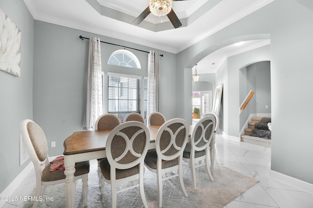 dining space with a tray ceiling and ornamental molding