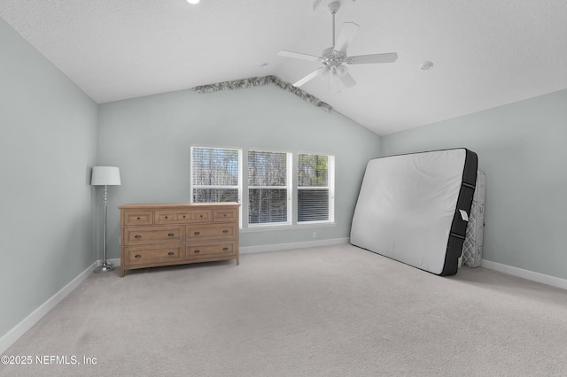 unfurnished bedroom featuring ceiling fan, light colored carpet, lofted ceiling, and a textured ceiling