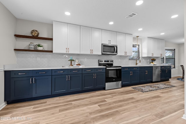 kitchen with sink, appliances with stainless steel finishes, white cabinetry, blue cabinets, and light wood-type flooring