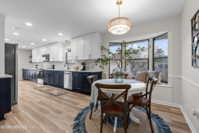 dining area with plenty of natural light, sink, a textured ceiling, and light wood-type flooring