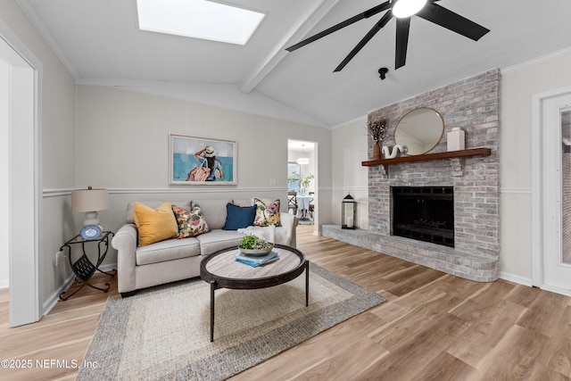 living room with lofted ceiling with beams, crown molding, a fireplace, and light hardwood / wood-style floors