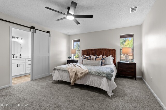 bedroom with light carpet, sink, multiple windows, and a barn door